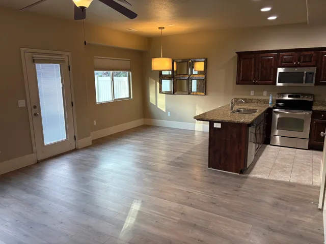 Open concept living area with wood-finish flooring, a kitchen island with sink, and dark wood cabinetry