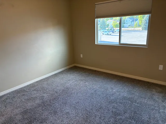 Neutral tone walls with white trim, gray carpet, and a window with blinds