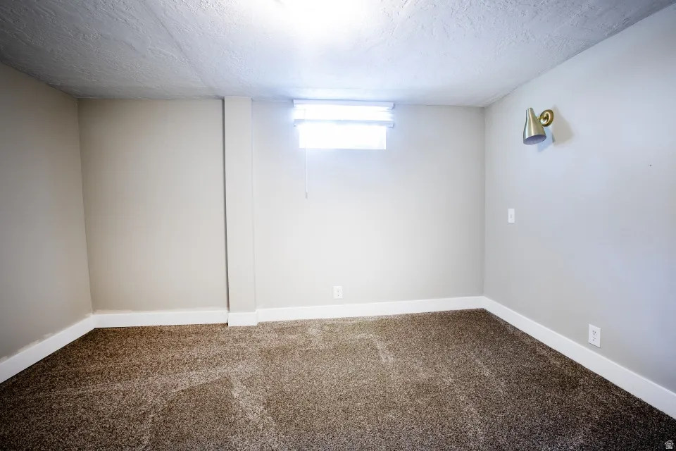 Neutral-toned walls, textured ceiling, and low-pile carpet flooring