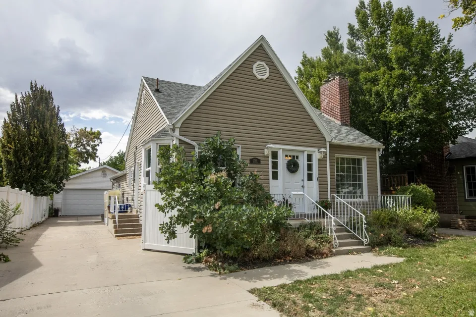 Gable roofline, brick chimney, bay window, white picket fence, and detached garage