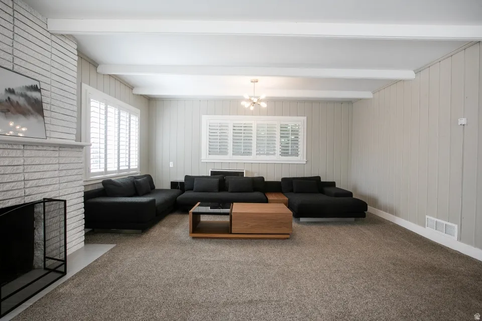 Living area with a white brick fireplace, white ceiling beams, and board and batten wall paneling