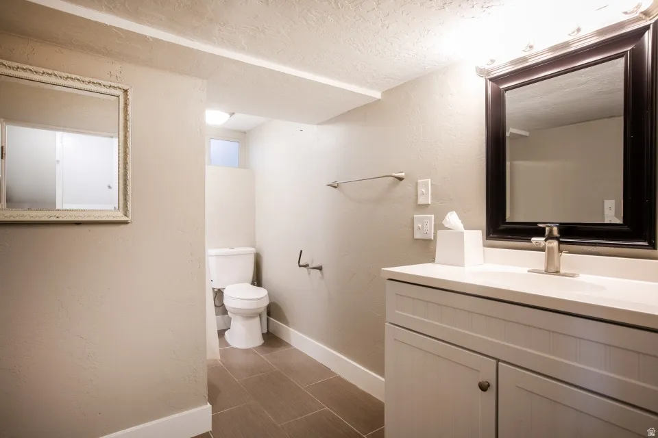 Vanity with integrated sink, rectangular framed mirror, brushed nickel faucet, and ceramic tile flooring