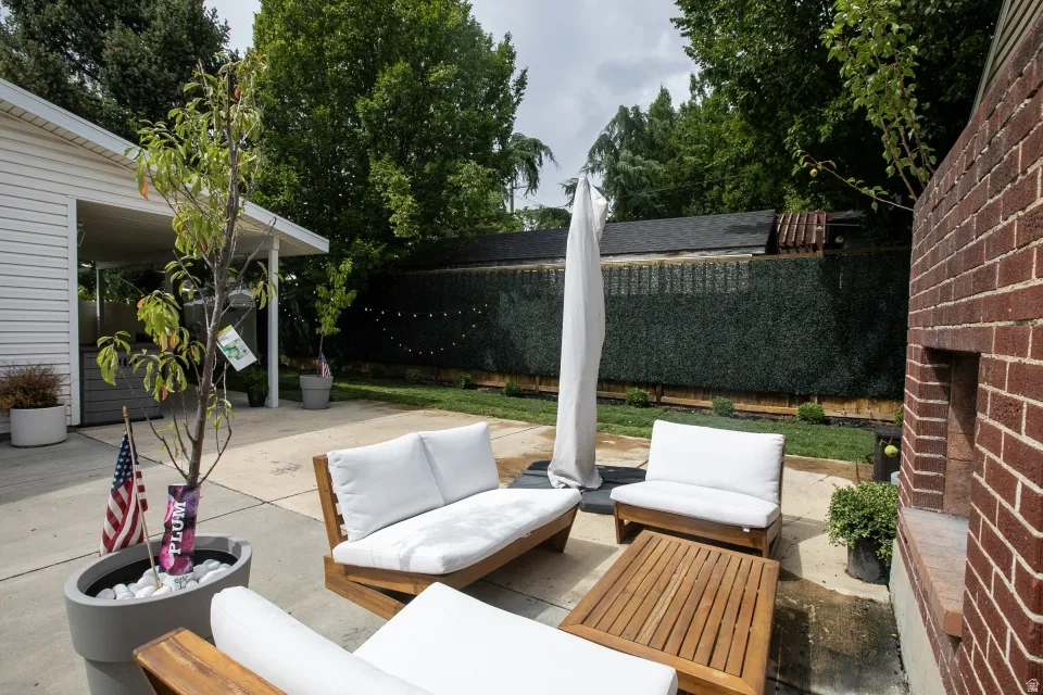 Poured concrete patio with a brick structure and green privacy fencing