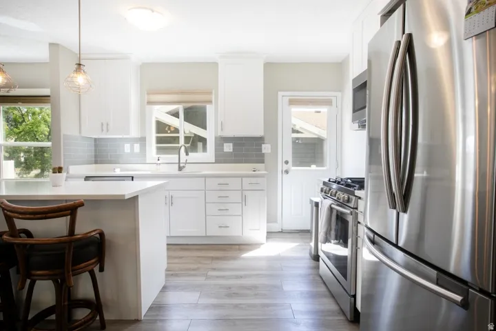 Kitchen featuring white cabinetry, gray subway tile backsplash, white countertops, and stainless steel appliances