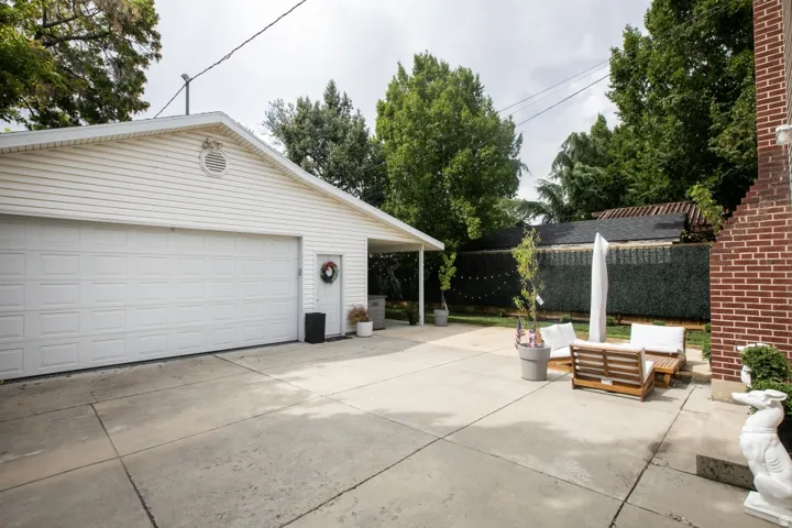 Attached two-car garage with white paneled door, dedicated side entry, and carport extension