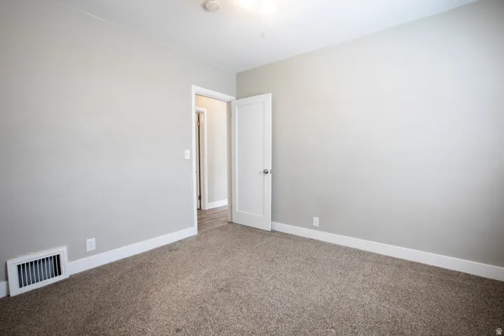 Neutral tone wall paint, light-colored carpeting, white trim, and a classic white door