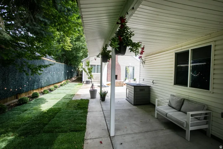 Covered patio with concrete flooring, siding exterior, and landscaped yard with a privacy fence