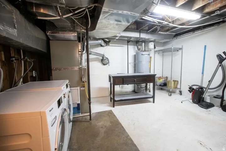 Laundry area with a washer and dryer, exposed ductwork, and a water heater