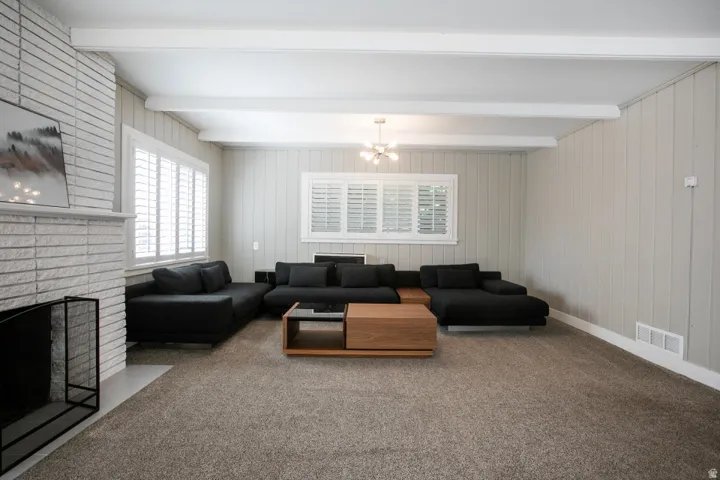 Living area with a white brick fireplace, white ceiling beams, and board and batten wall paneling
