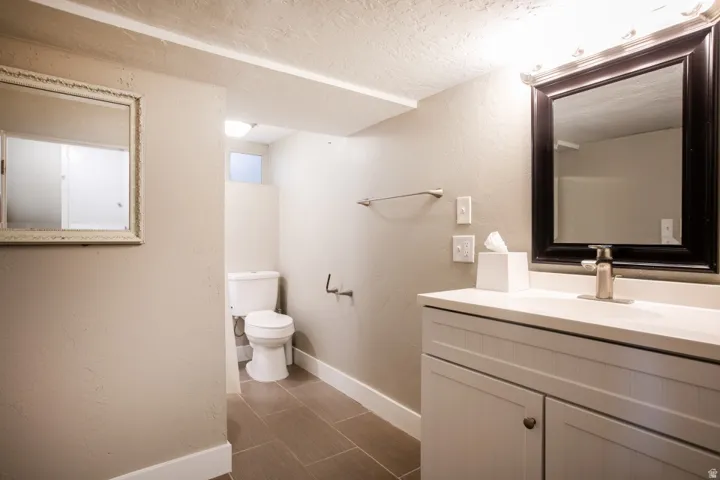 Vanity with integrated sink, rectangular framed mirror, brushed nickel faucet, and ceramic tile flooring