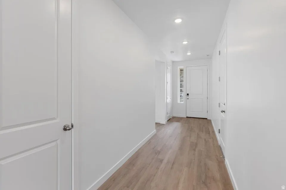 Hallway with recessed lighting, wood-finish flooring, white doors, and a front entry door with a sidelight window