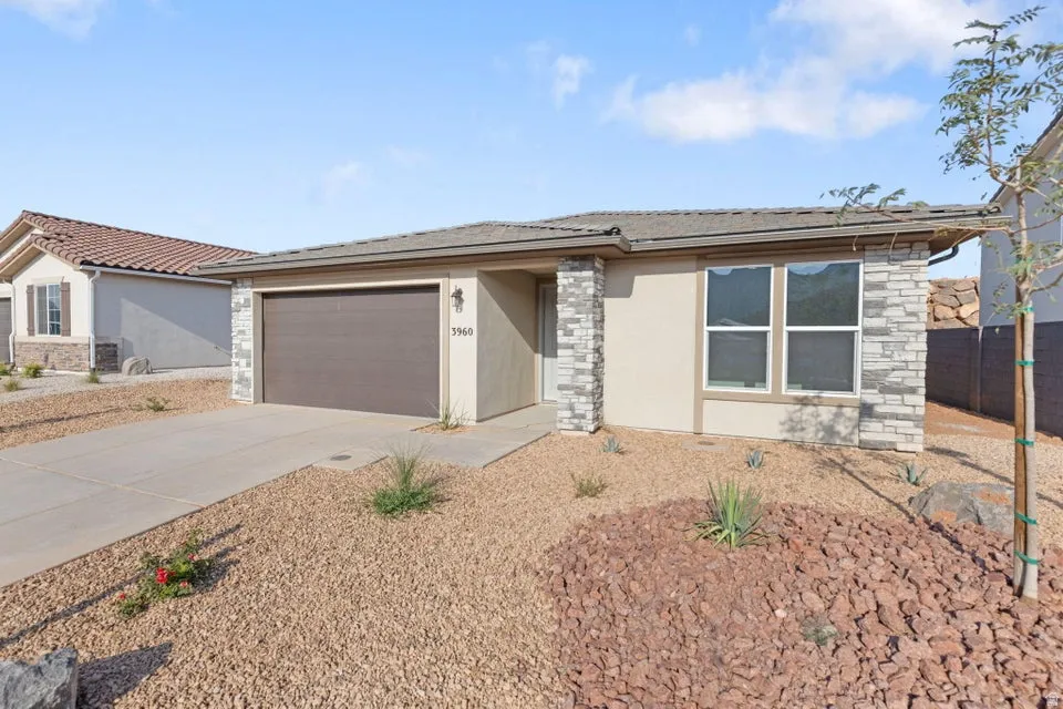 Stucco exterior with stone accents, attached garage, and a concrete driveway