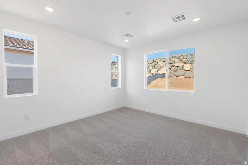 Recessed lighting, multiple windows, and light gray carpeting
