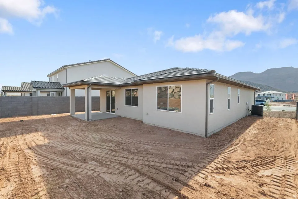 Rear exterior featuring a covered patio, multiple windows, and a block wall perimeter