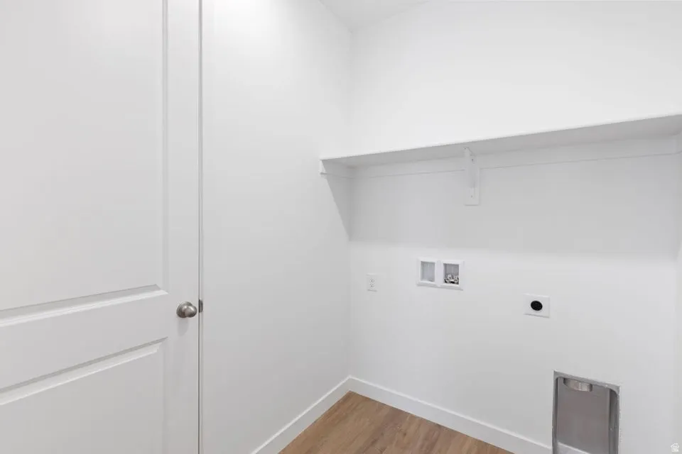 Dedicated utility space featuring a built-in shelf, wood-finish flooring, and a panel door