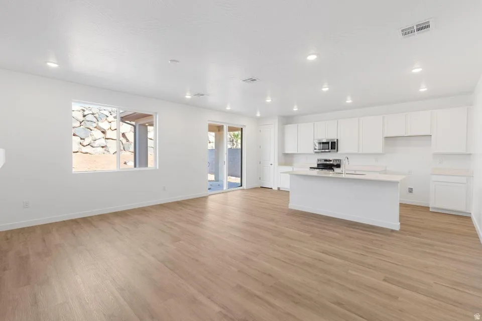 Open-concept living space with wood-finish flooring, recessed lighting, and white walls