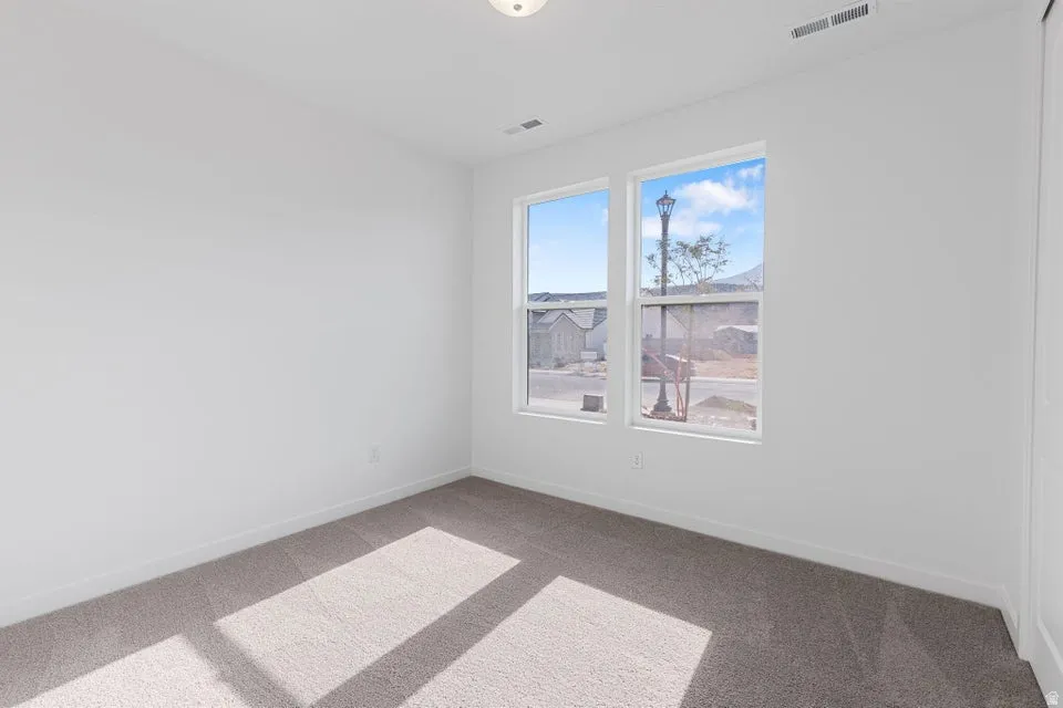 Plush carpeting, neutral wall tones, two large windows, and a flush-mount ceiling light fixture