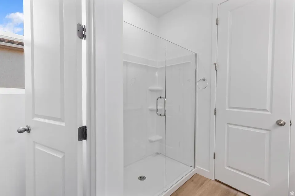 Enclosed shower with clear glass door, white shower surround, and integrated shelving