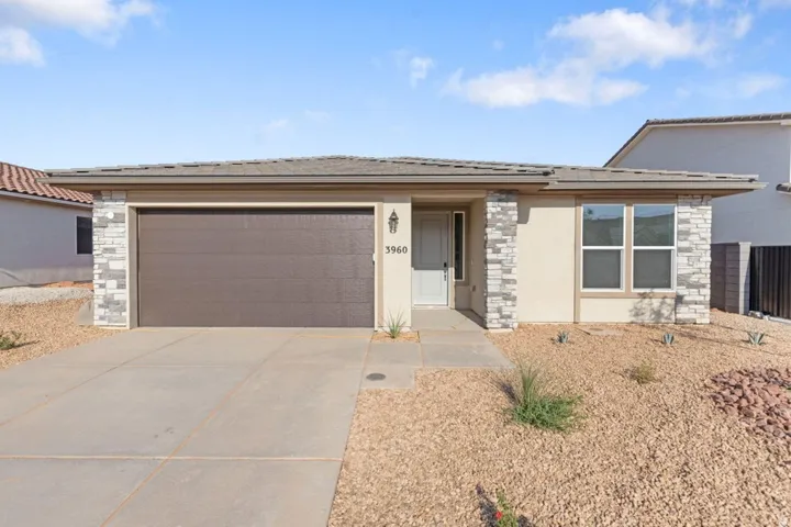Single-story residence featuring a tile roof, stucco exterior, stone veneer accents, and an attached garage