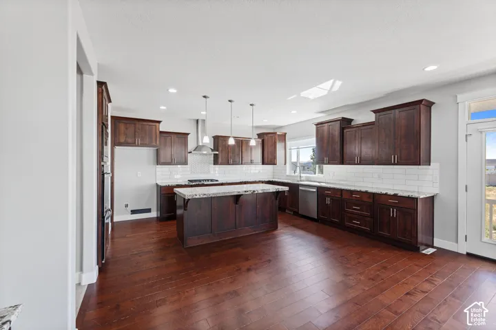 Spacious kitchen featuring dark wood cabinetry, granite countertops, subway tile backsplash, a central island, and wood-finish flooring