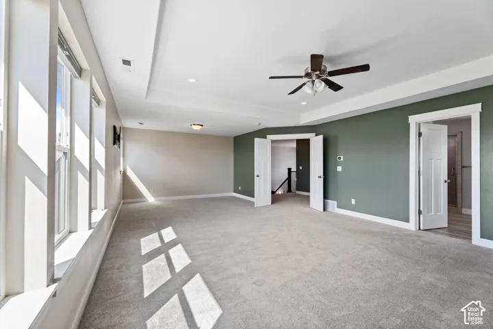 Tray ceiling, recessed lighting, ceiling fan, carpeted flooring, and multiple windows