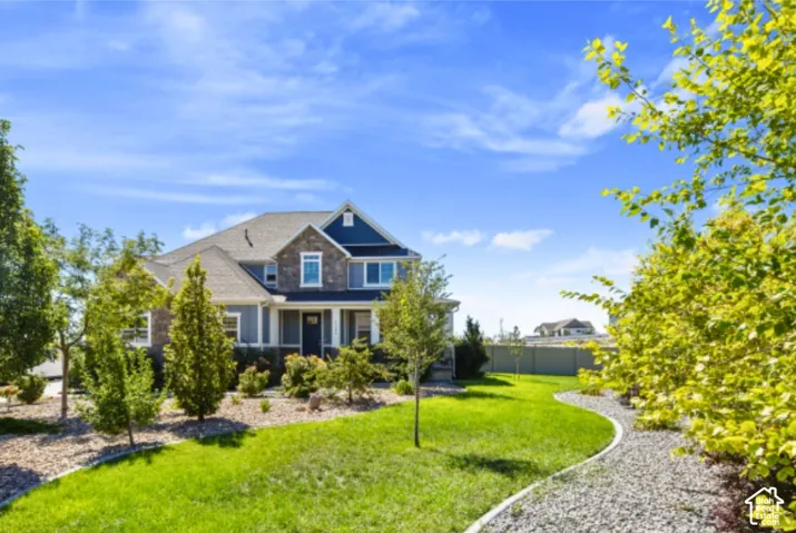 Two-story residence featuring a stone and siding exterior, a front porch, and a dark front door