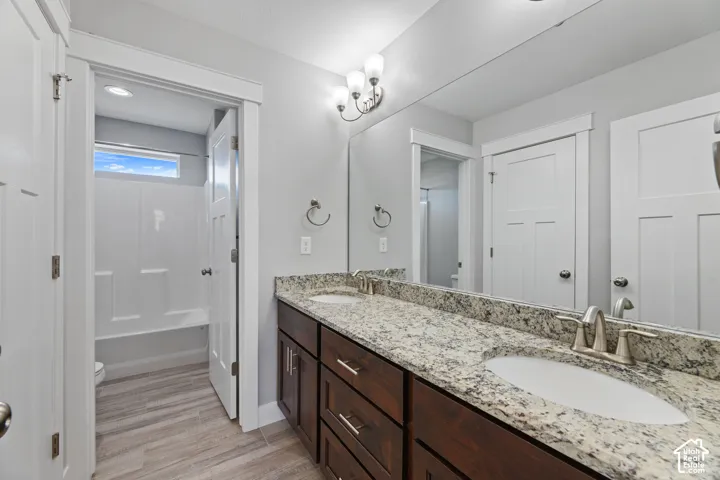 Dual sink vanity with dark wood-finish cabinetry, light-toned stone-finish countertop, and integrated white oval sinks