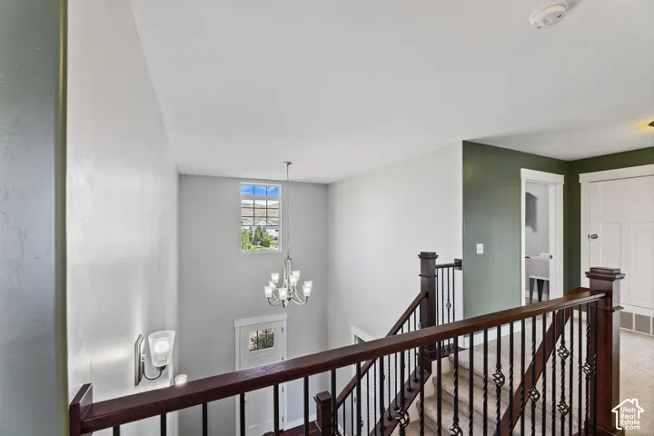 Staircase featuring dark wood newel posts and handrails, intricate black metal balusters, and light-toned carpeted treads