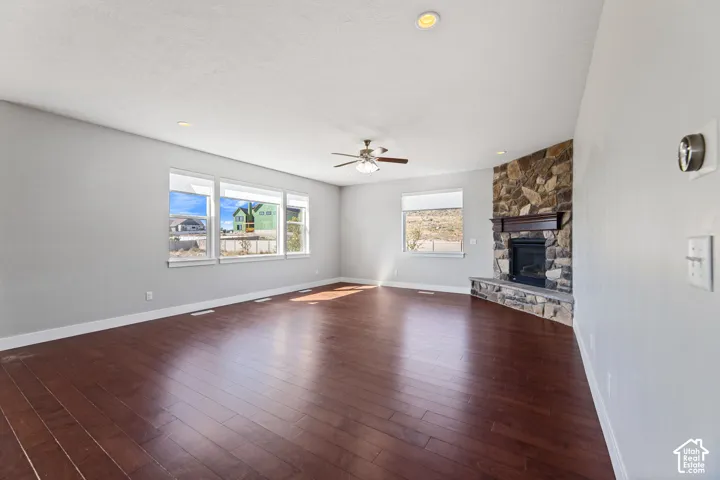 Hardwood-finish flooring, recessed lighting, and a stone-clad fireplace with a wood mantel