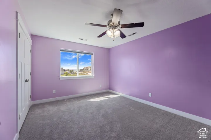 Textured carpeting, white trim, and a ceiling fan with integrated lighting