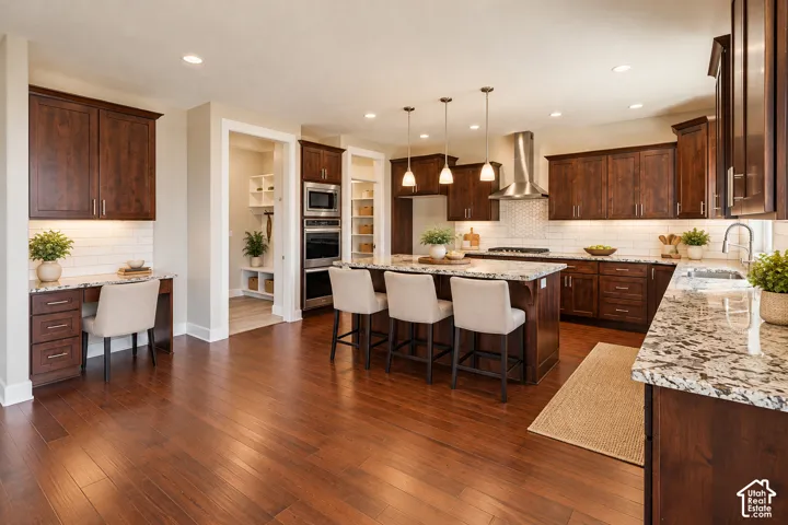 Kitchen featuring dark wood cabinetry, stone-surface countertops, subway tile backsplash, stainless steel double wall ovens, and wood-finish flooring