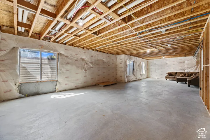 Expansive unfinished basement featuring exposed ceiling joists, concrete flooring, and multiple windows