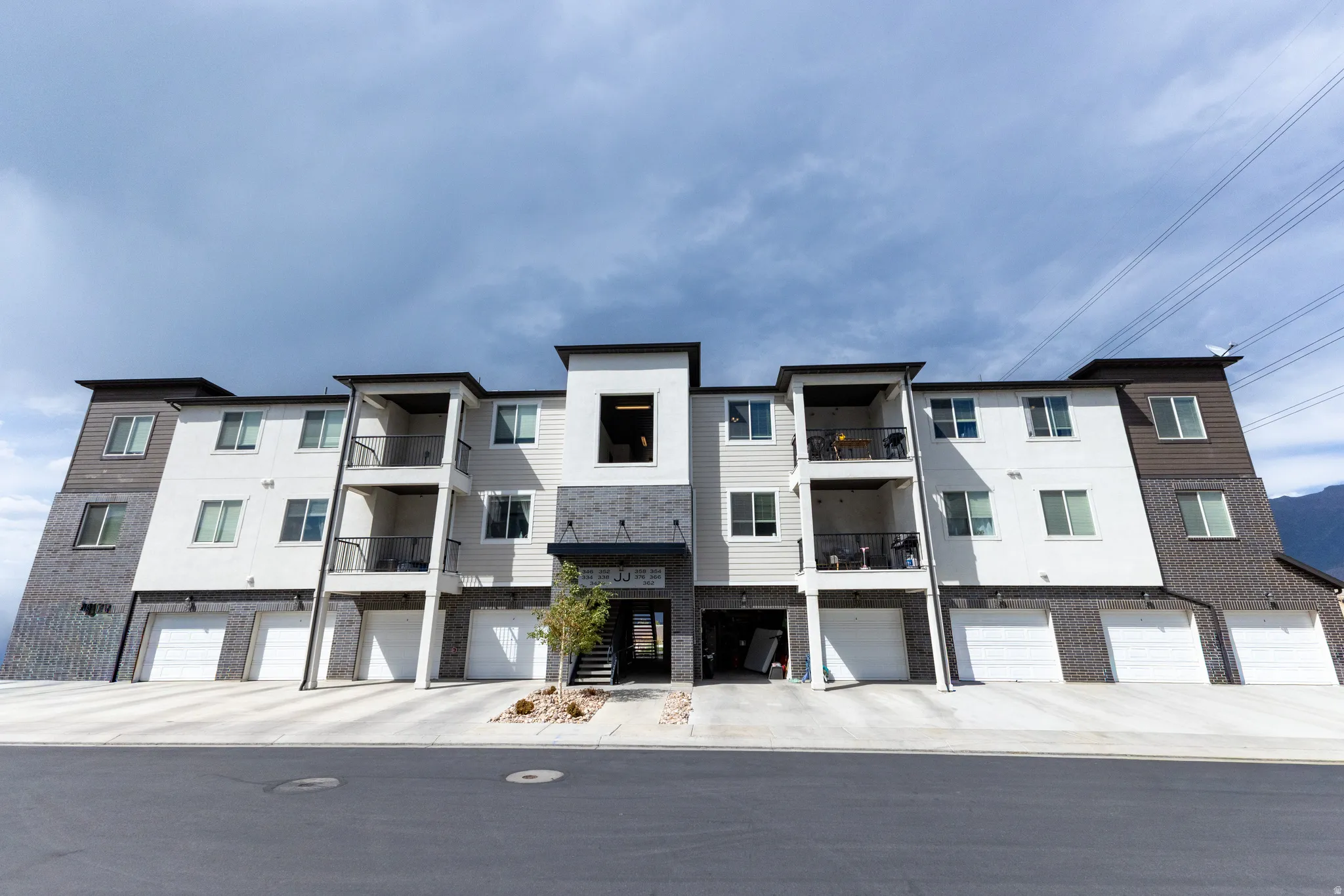 Contemporary multi-story building featuring white and dark siding with brick accents.