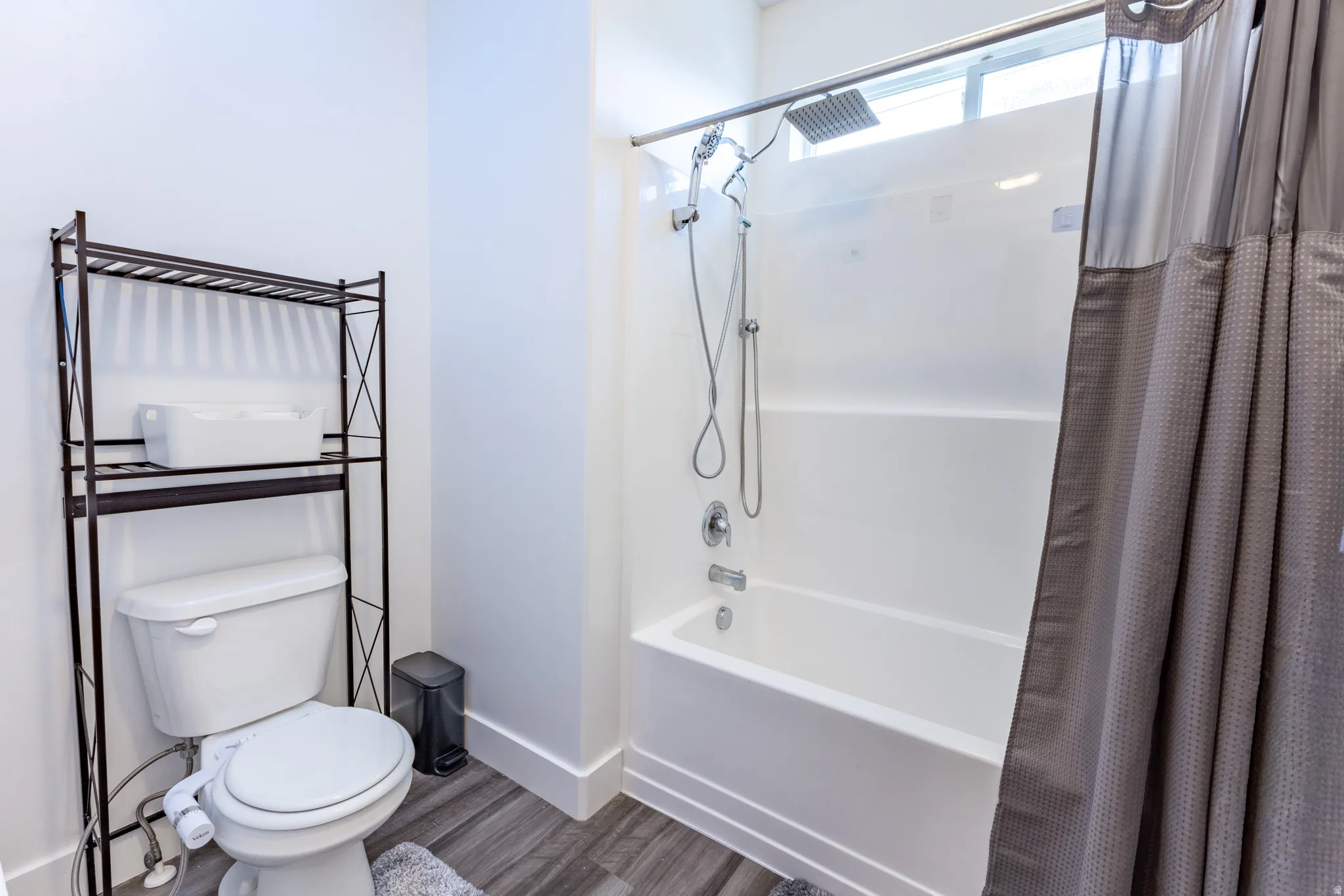 White bathtub and shower combination with a rain showerhead, handheld shower, and chrome fixtures