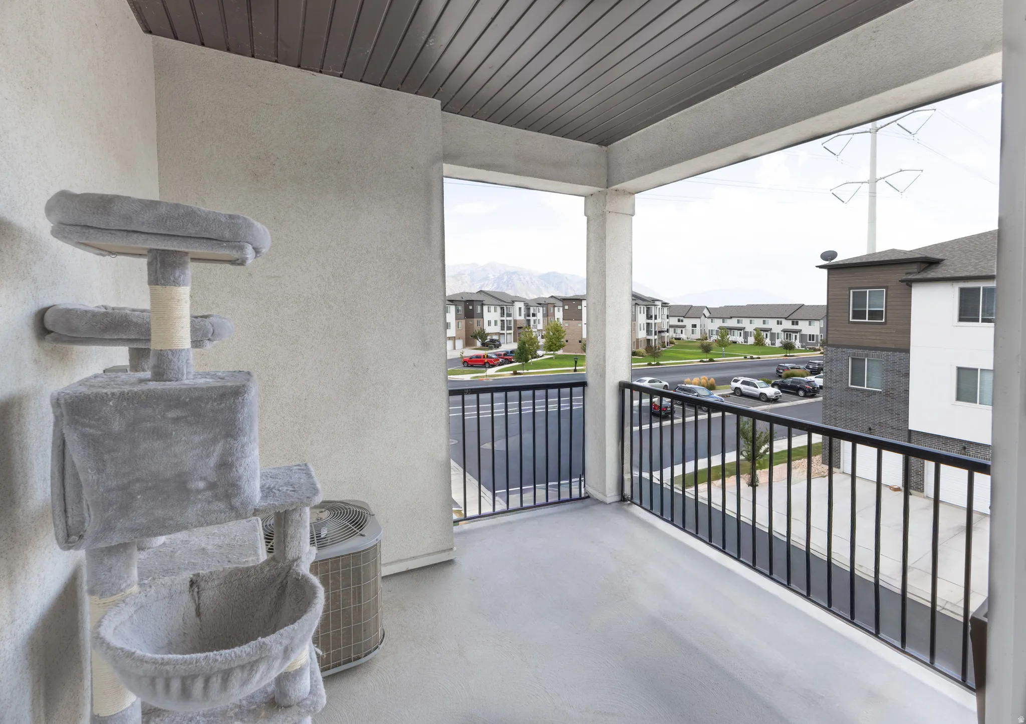 Balcony featuring a concrete floor, black metal railing, and a slatted ceiling