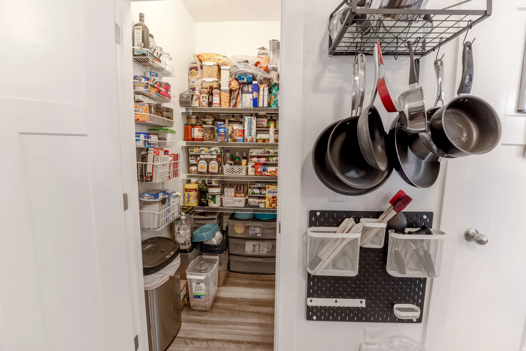 Walk-in pantry with extensive wire shelving, wood-finish flooring, and a white paneled door