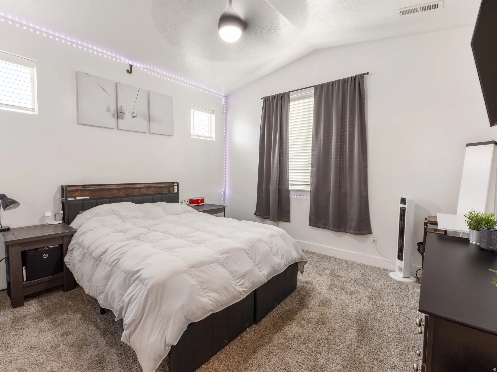 Vaulted ceiling, ceiling fan, carpet flooring, and multiple windows