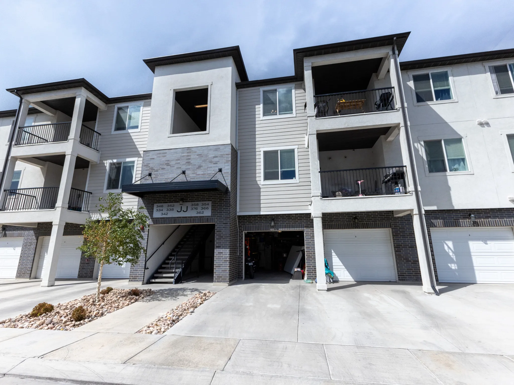 Multi-level residential building featuring a combination of white siding, gray siding, and dark brick-style facade