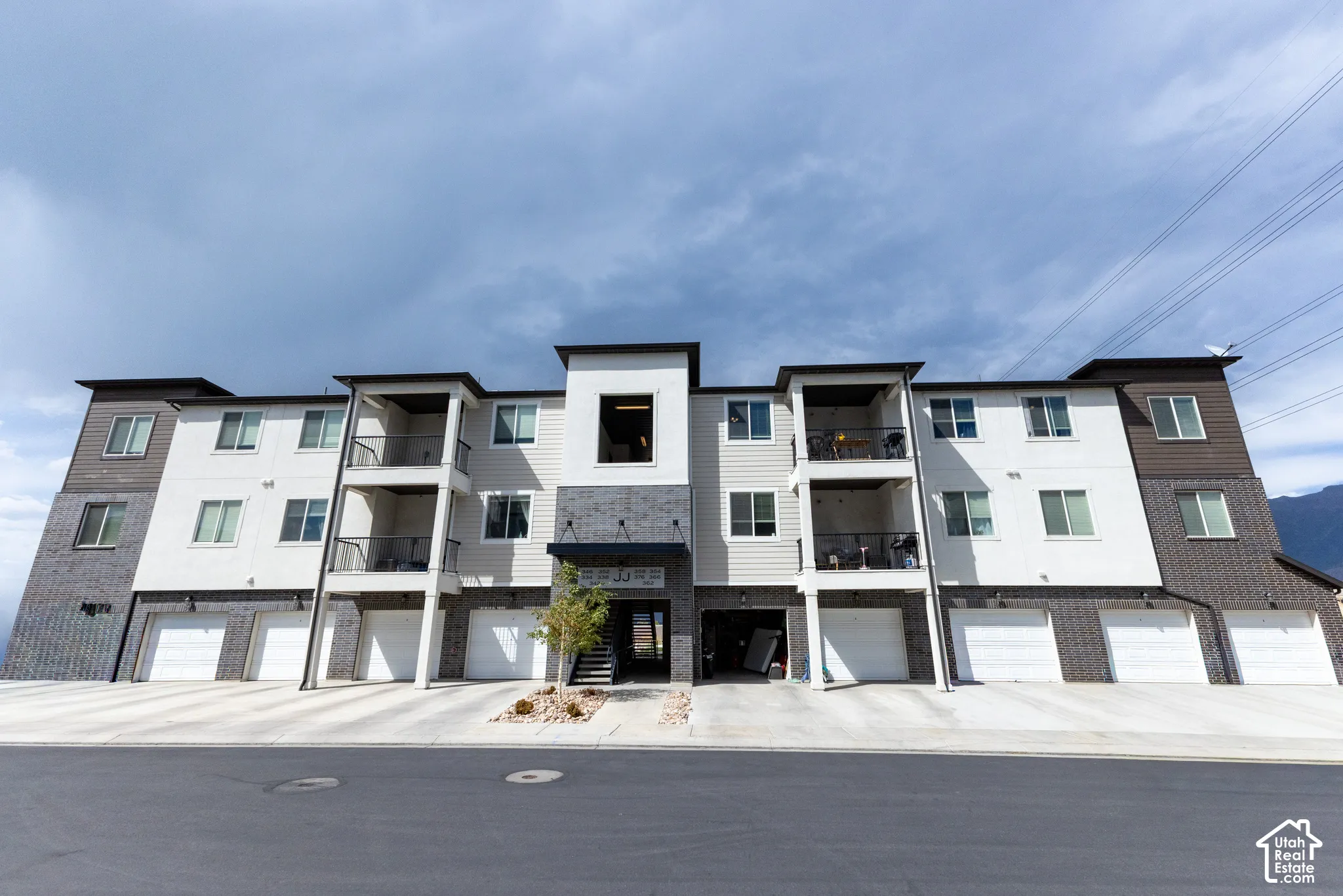 Contemporary multi-story building featuring white and dark siding with brick accents.