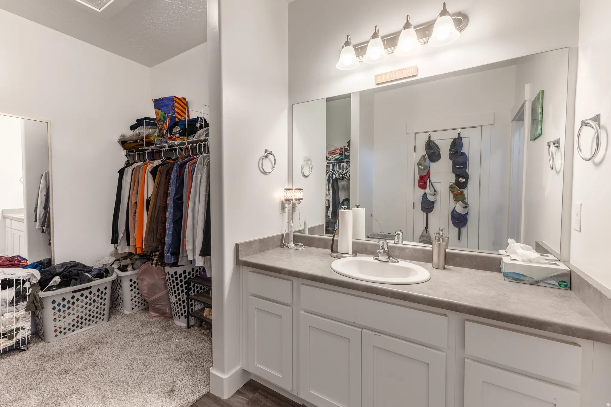 White vanity with recessed panel cabinetry and an integrated sink, full-width mirror, and a three-light vanity fixture