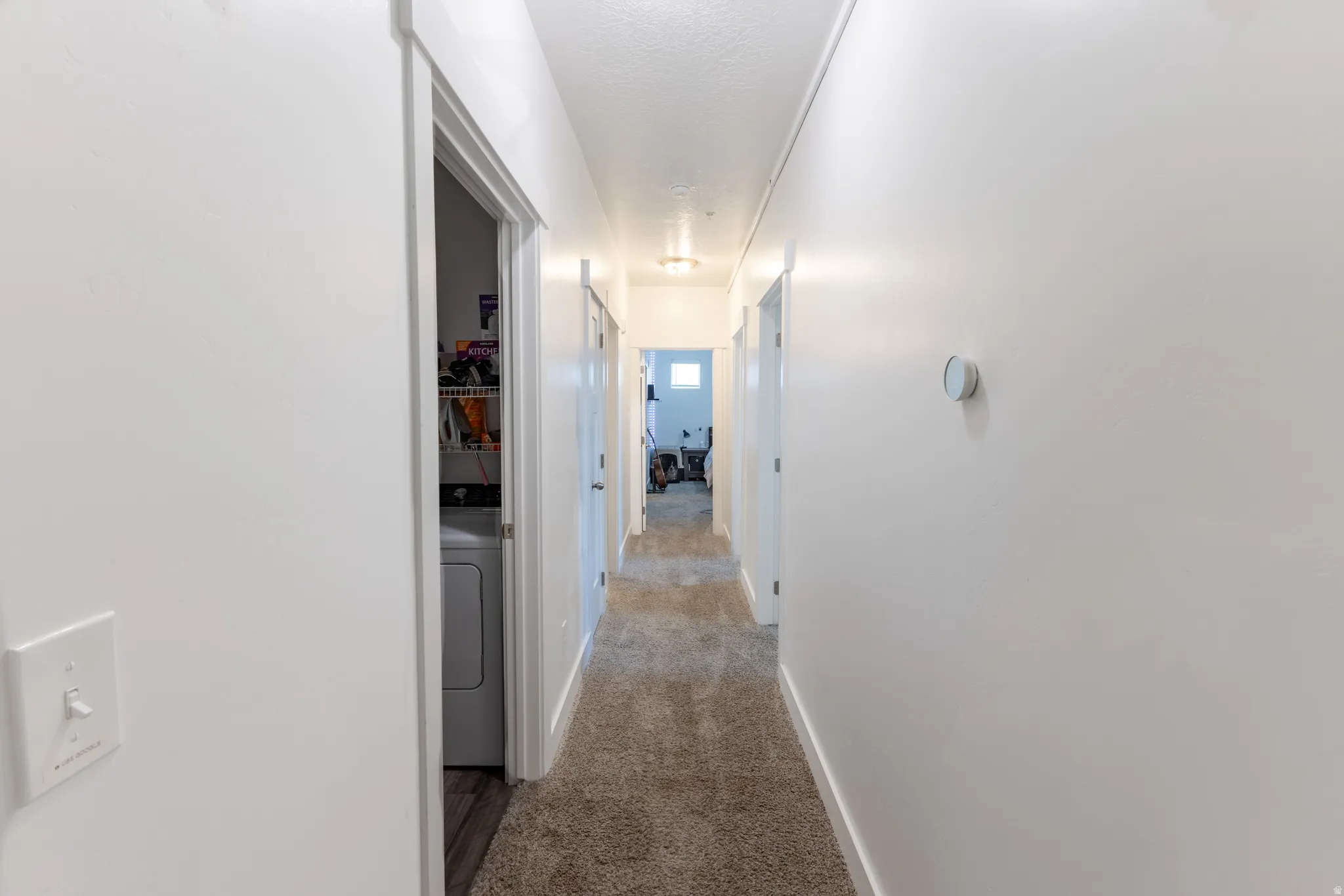 Hallway with light-colored carpet flooring and white walls