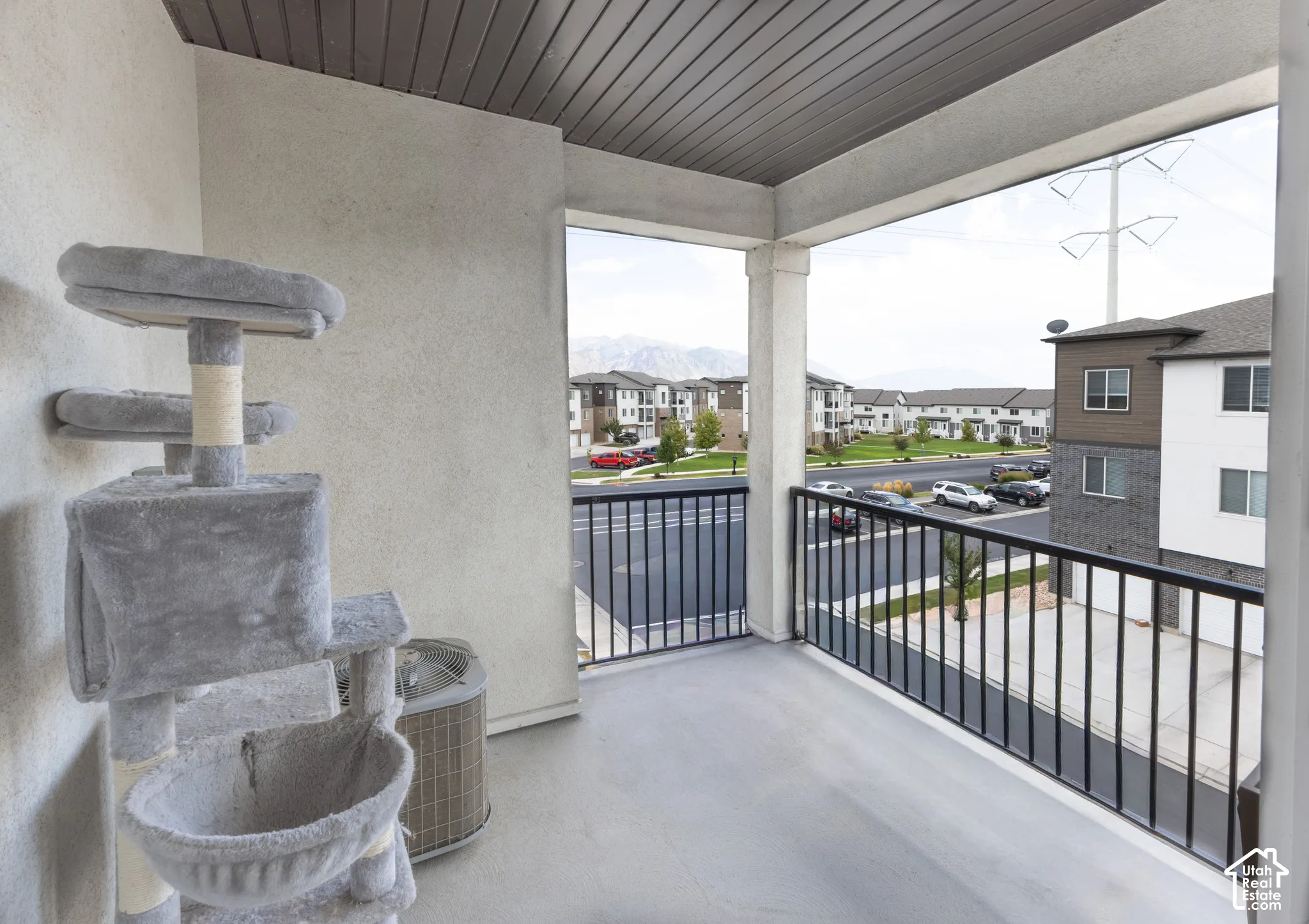 Balcony featuring a concrete floor, black metal railing, and a slatted ceiling