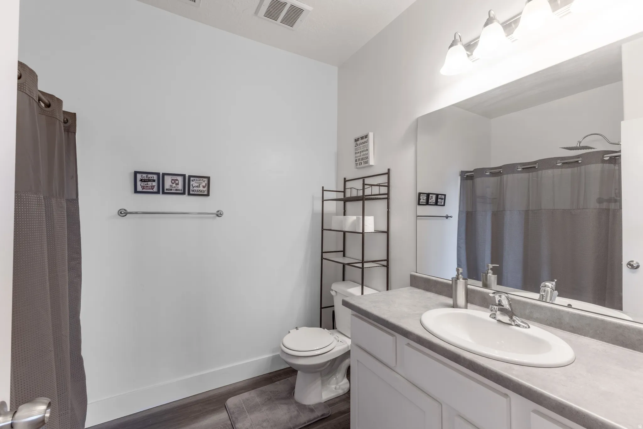 Bathroom featuring a vanity with an integrated sink, broad wall mirror, and modern lighting fixture