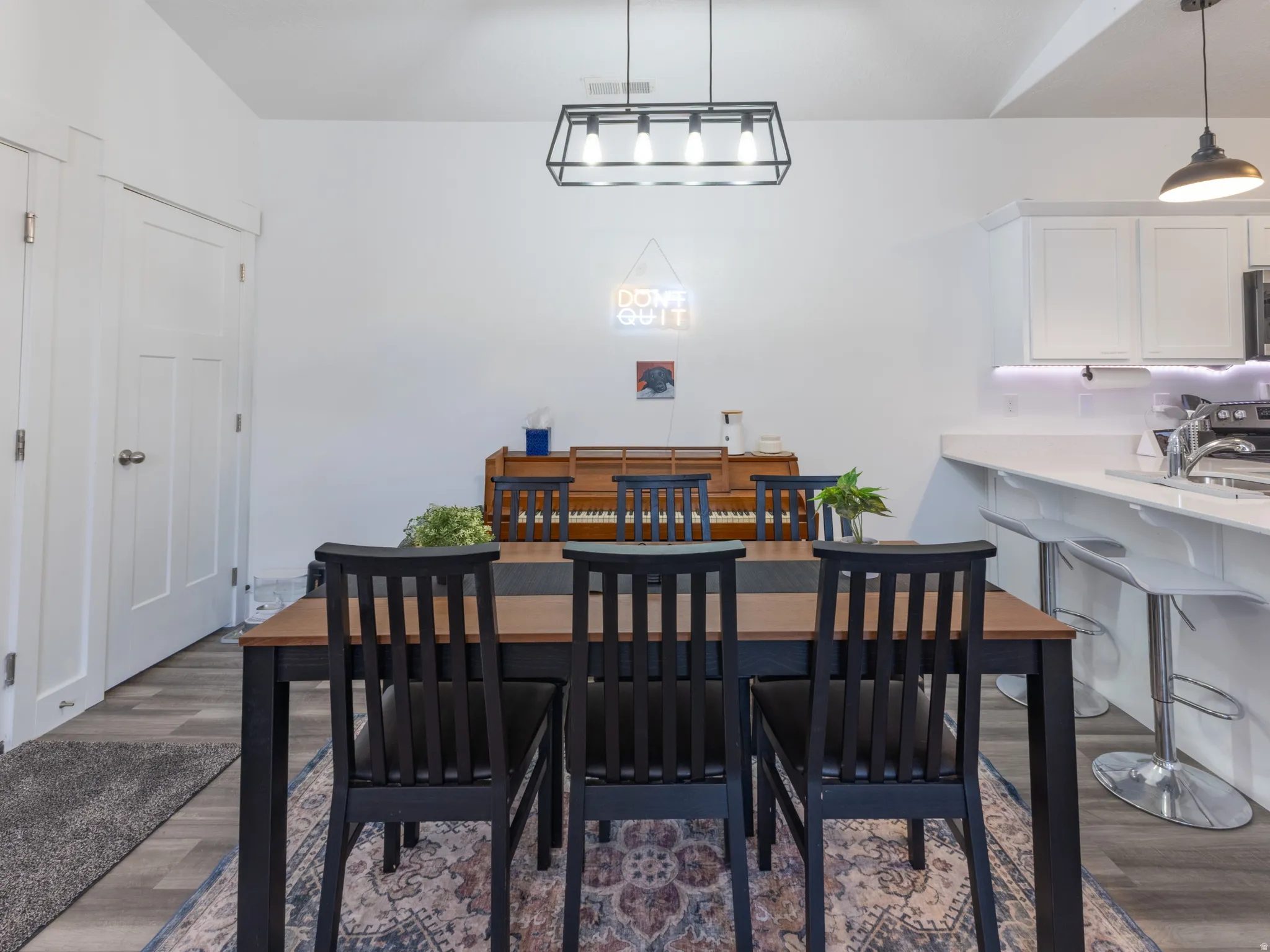 Open concept dining area with wood-finish flooring, a linear pendant light fixture, and white walls