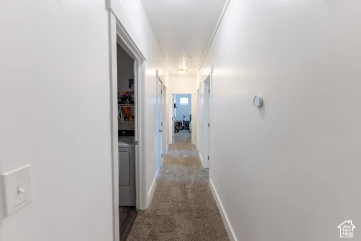 Hallway with light-colored carpet flooring and white walls