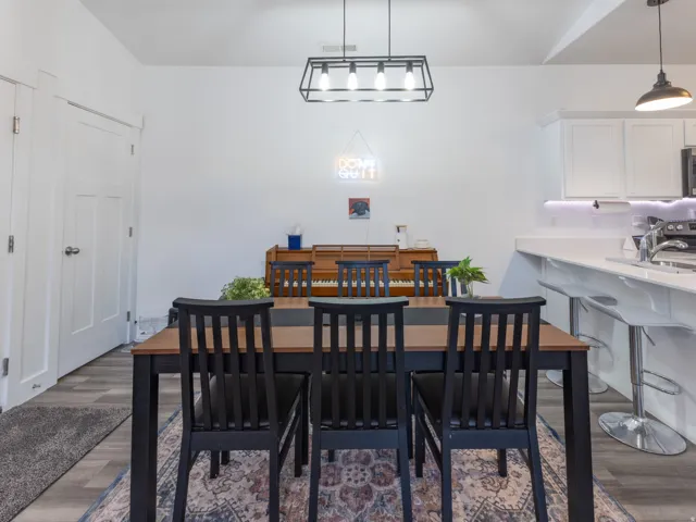 Open concept dining area with wood-finish flooring, a linear pendant light fixture, and white walls