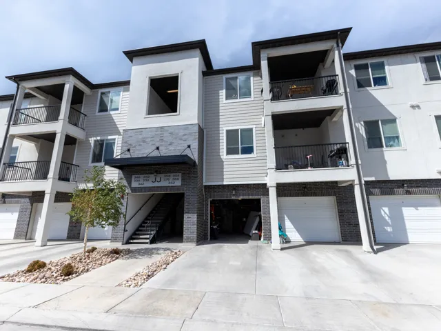 Multi-level residential building featuring a combination of white siding, gray siding, and dark brick-style facade