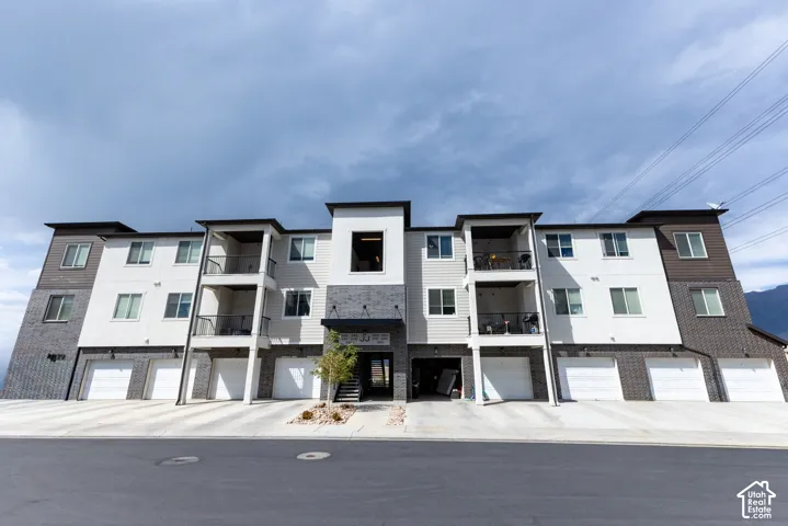 Contemporary multi-story building featuring white and dark siding with brick accents.