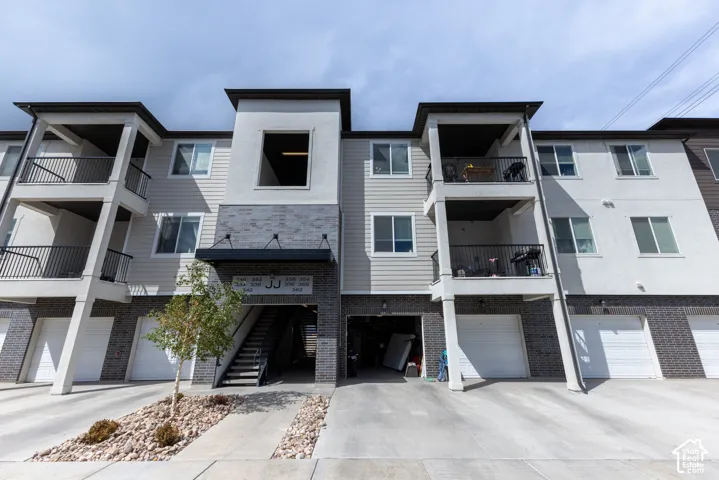 Multi-story building with stacked balconies, individual garage doors, and a stone facade accent