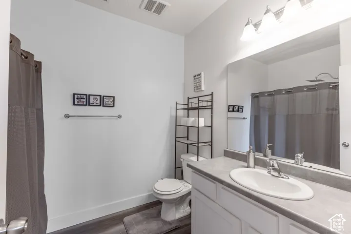 Bathroom featuring a vanity with an integrated sink, broad wall mirror, and modern lighting fixture
